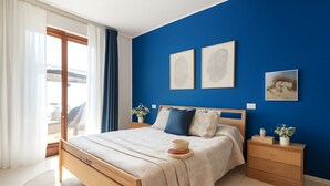 A bedroom with a bed, a nightstand, a dresser, and a window with curtains. - Elegant two-room apartment with wifi, air conditioning, central area (Sardegna)