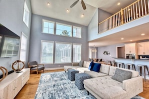 A spacious living room with a large sectional sofa, a wooden coffee table, and a ceiling fan.