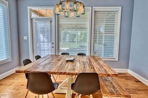 A dining room with a wooden table, four chairs, and a chandelier.