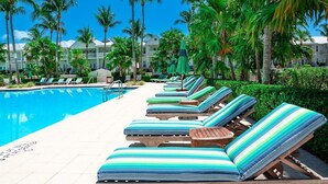Un espace aménagé au bord de la piscine, avec des chaises longues et des palmiers.