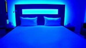 A bed with a headboard and two pillows in a room with blue lighting. - Hotel Kanha Ujjain (Ujjain)