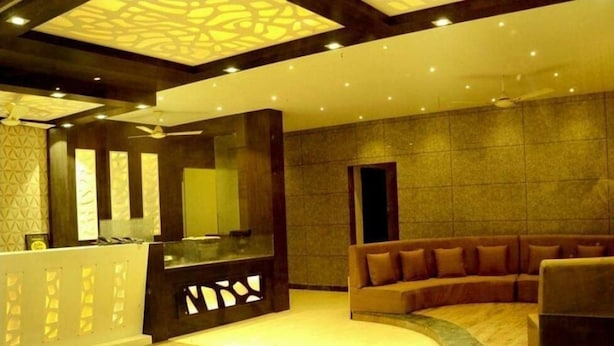 A modern lobby with a reception desk, a large mirror, a sofa, and a patterned ceiling. - Hotel Kanha Ujjain (Ujjain)