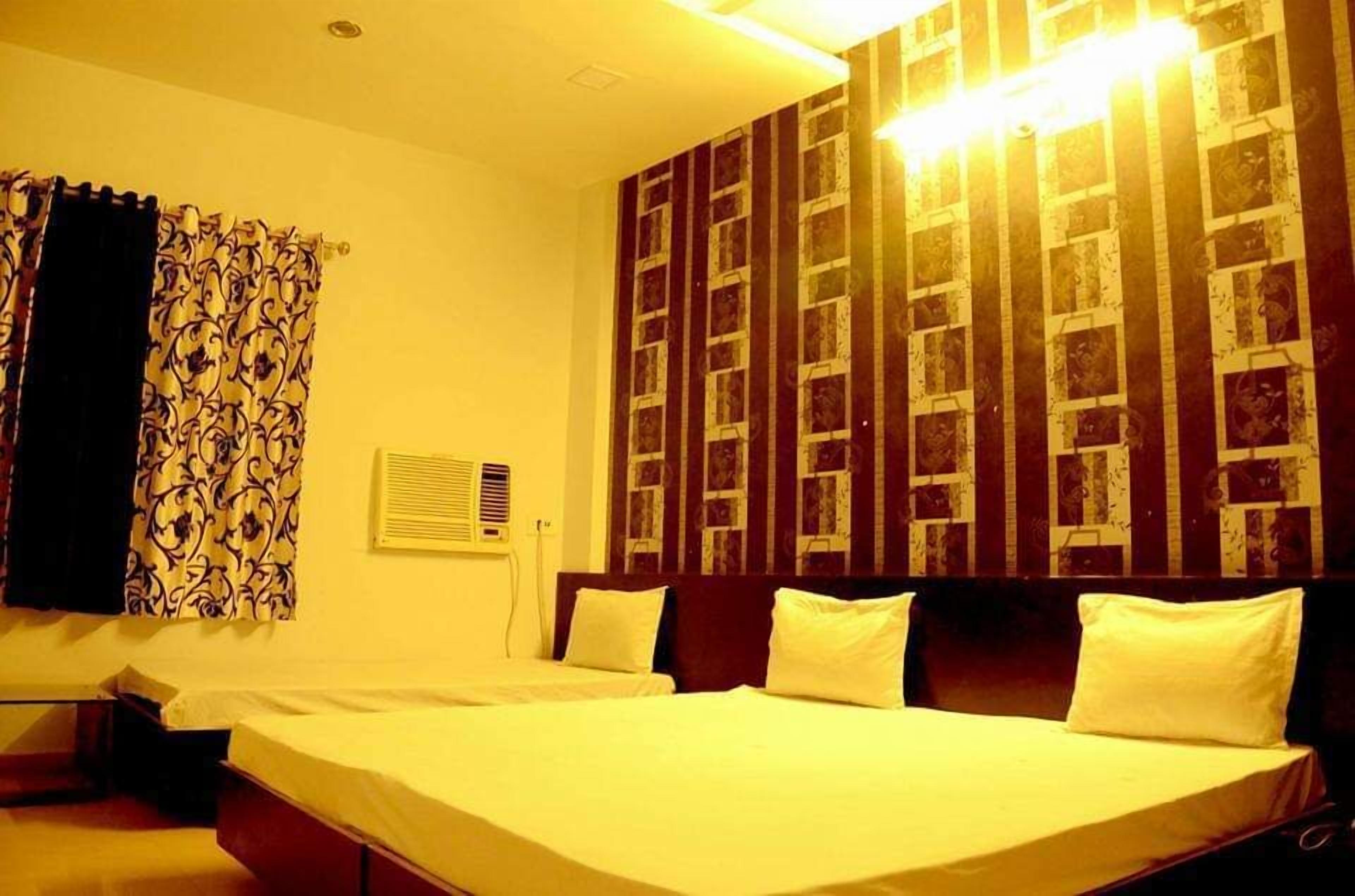 A hotel room with two beds, a patterned curtain, a wall-mounted air conditioner, and a decorative wall panel.