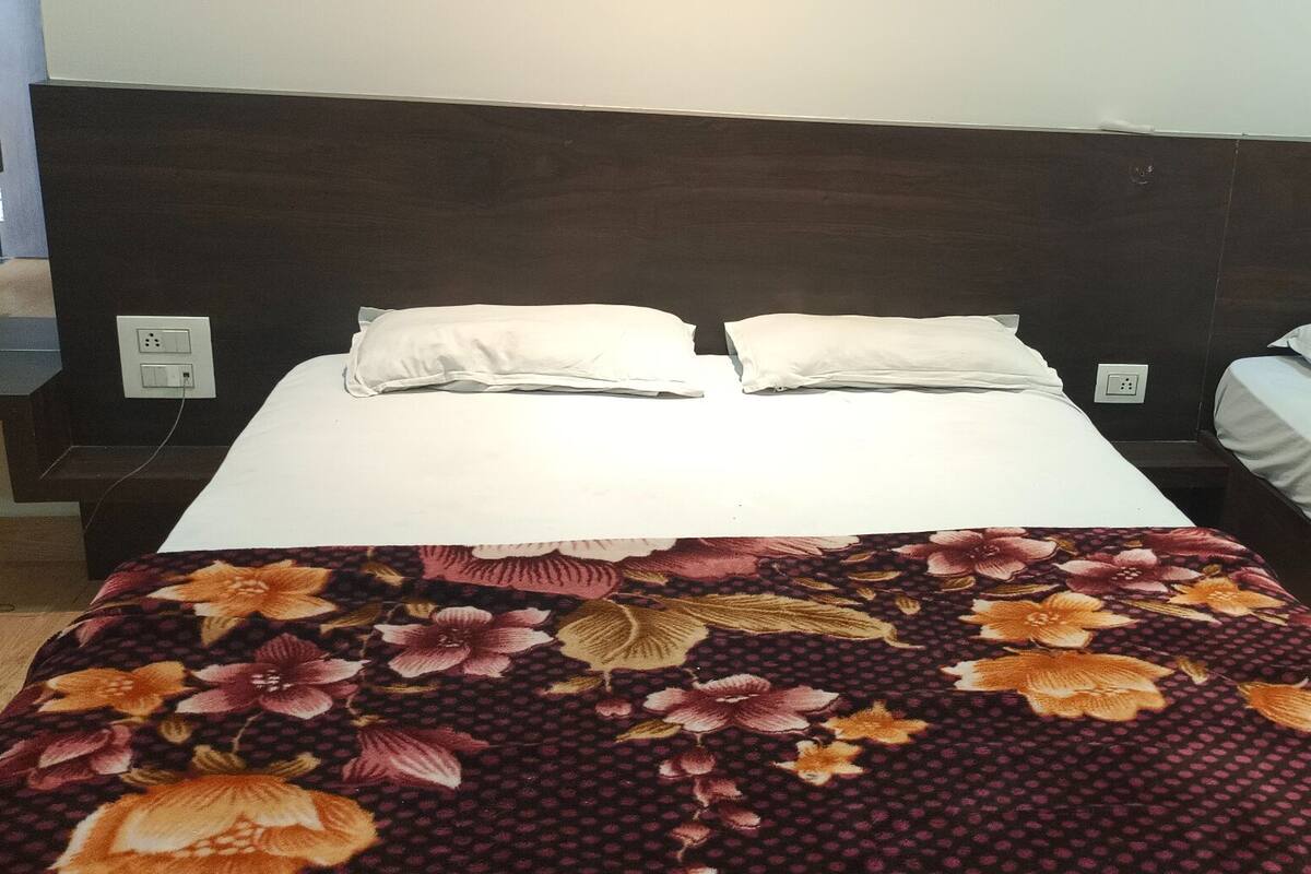 Una habitación de hotel con una cama grande, una cama más pequeña y una mesita de noche.