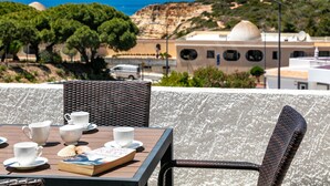 Una mesa con tazas y platillos blancos, un libro y conchas marinas.