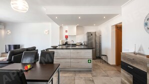 Una sala de estar moderna con un sofá, una mesa de comedor y una cocina equipada con refrigerador y armarios.