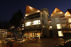 A modern building with a courtyard, outdoor seating, and illuminated windows. - Hotel Arif Castle (Nainital)
