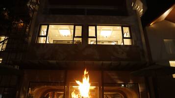 Un edificio de varios pisos con una chimenea decorativa en la parte frontal, amplias ventanas y una escalera visible.