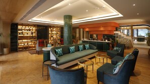 Um hall moderno com sofá, poltronas, mesinha de centro, área de bar e estante de livros.