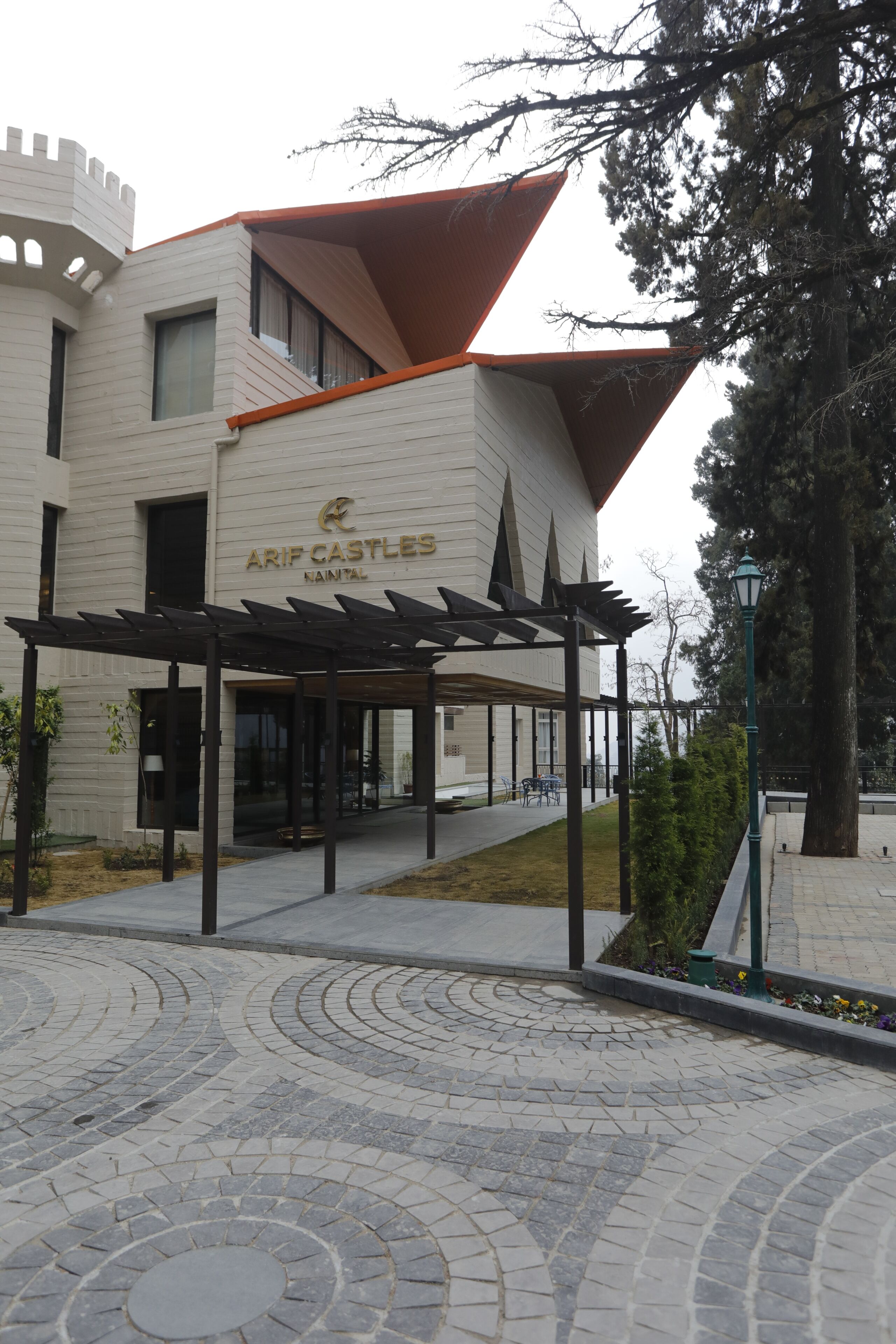 A modern building with a castle-like facade, a covered entrance area, and a paved courtyard.