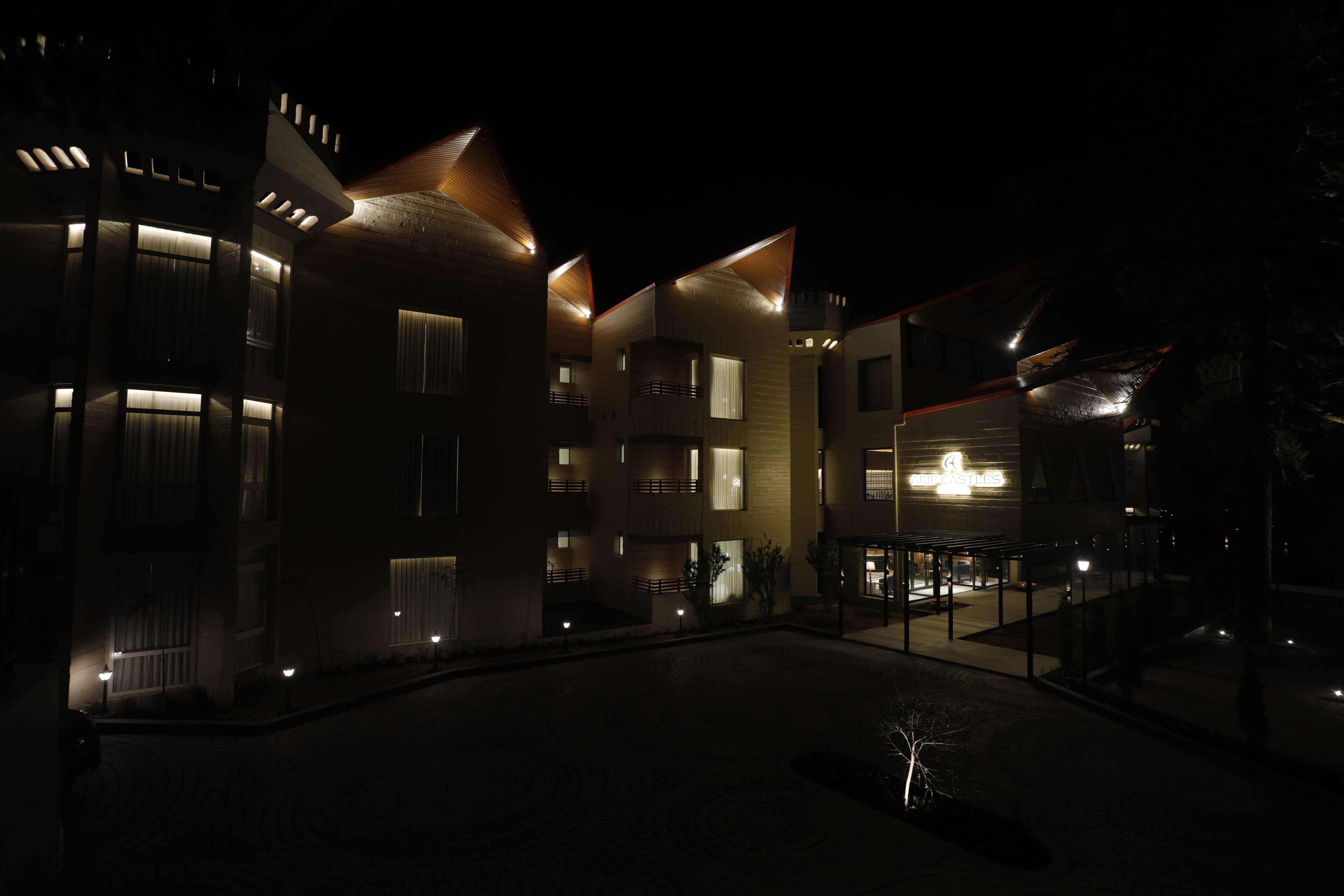 A multi-story hotel with illuminated windows and a well-lit entrance area.