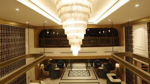 Um hall com um lustre grande, área de estar e uma escadaria.
