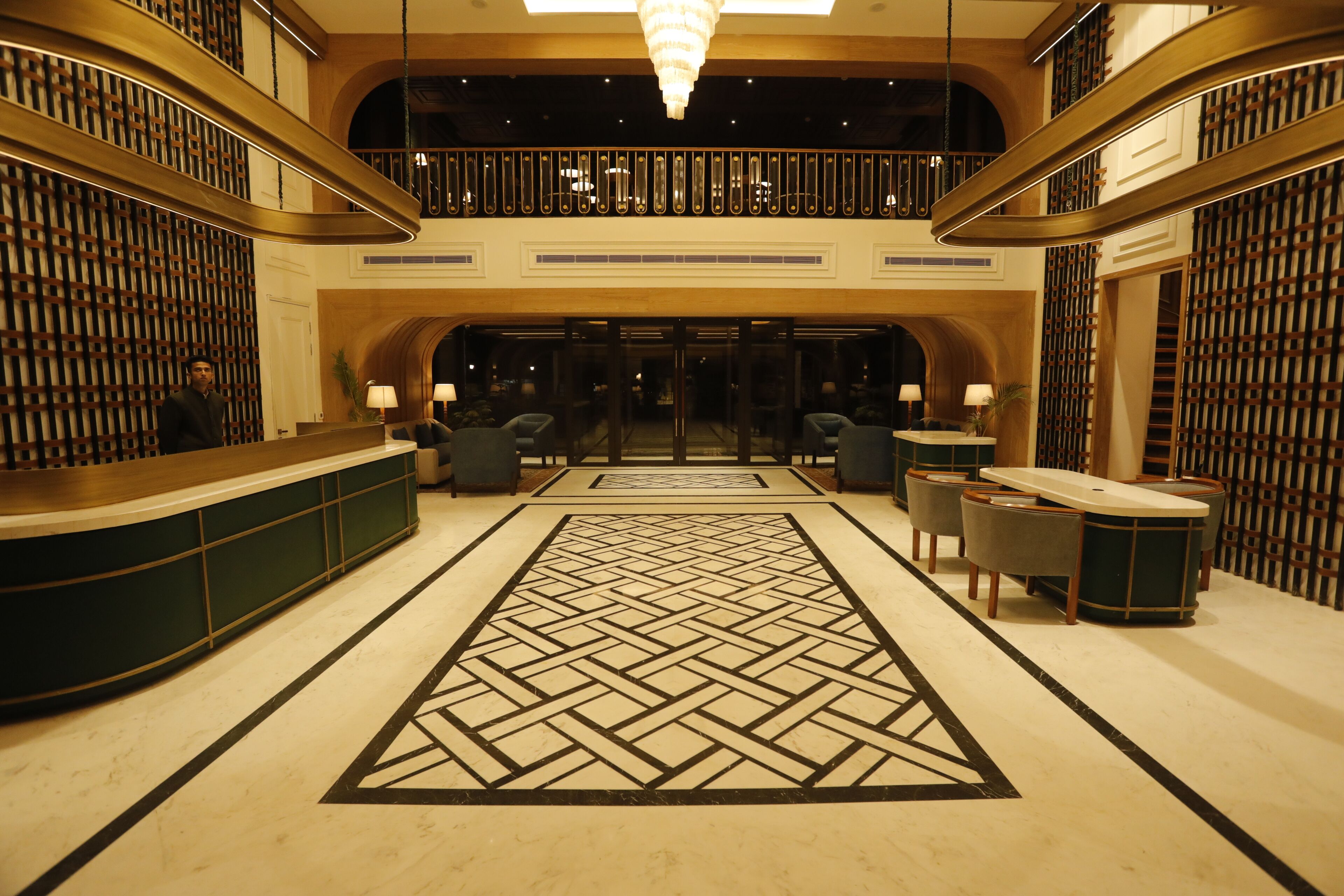 Un hall d’hôtel comprenant un comptoir d’accueil, un espace salon et un tapis décoratif à motifs géométriques.