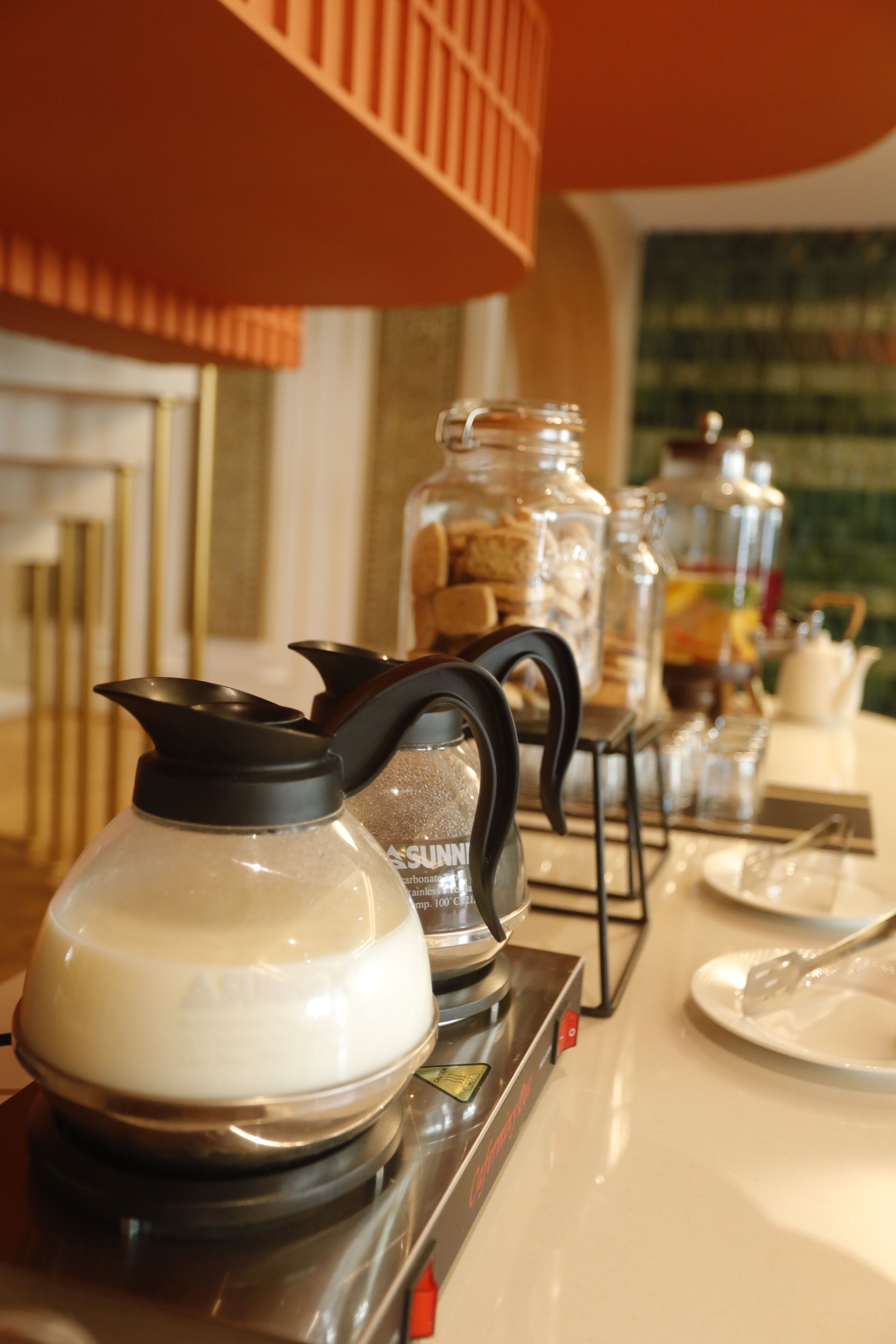 A breakfast setup with a coffee pot, sugar container, and a jar of cookies.