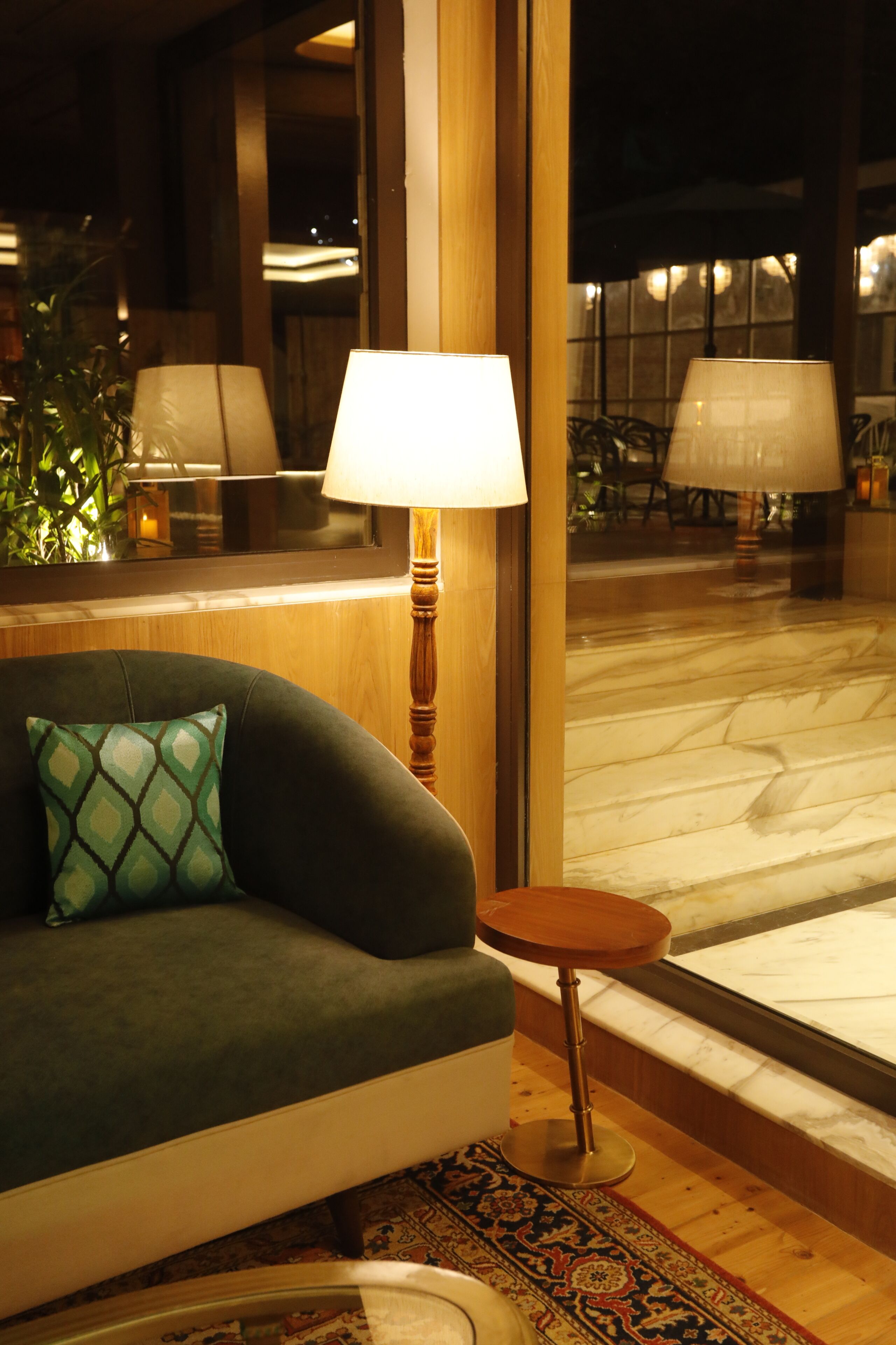 Une pièce comprenant un canapé, une lampe, une petite table ronde et un tapis à motifs.