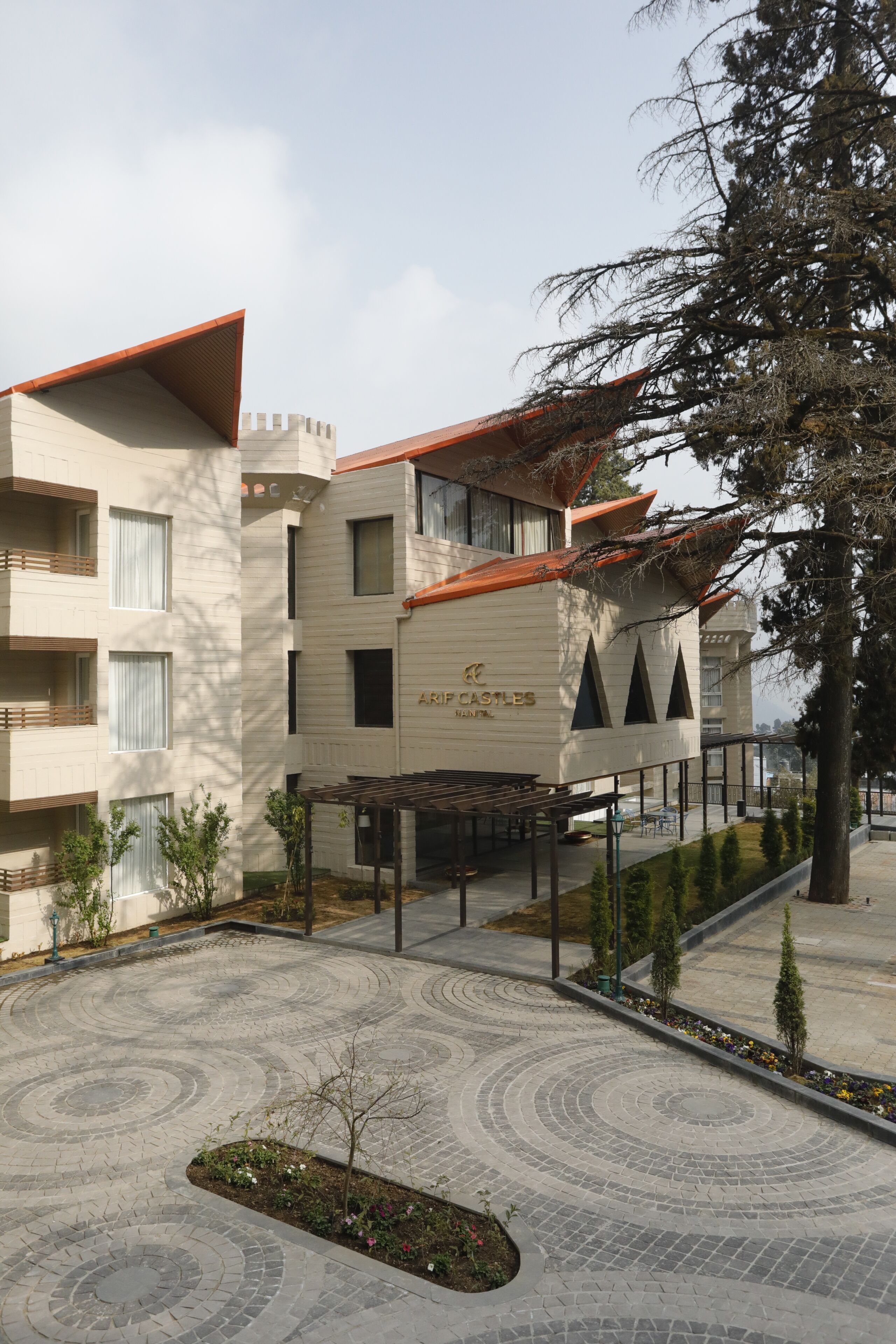 A hotel with a castle-themed facade, a courtyard with patterned paving, and a covered outdoor seating area.