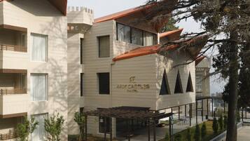 A hotel with a castle-themed facade, a courtyard with patterned paving, and a covered outdoor seating area.