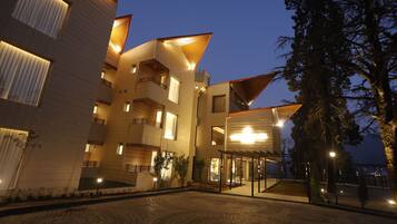 A modern building with multiple balconies, a courtyard with patterned paving, and a well-lit entrance.