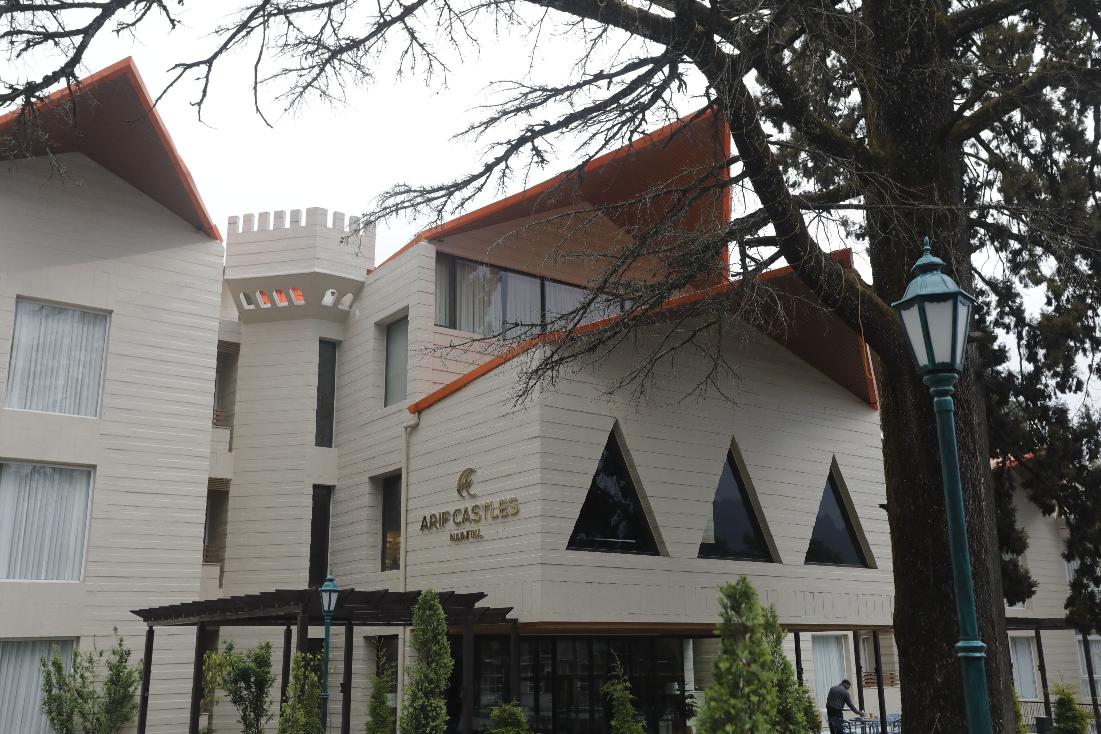 A building with a castle-like facade, labeled 'ARIC CASTLES,' featuring a modern design with triangular windows and a pergola.
