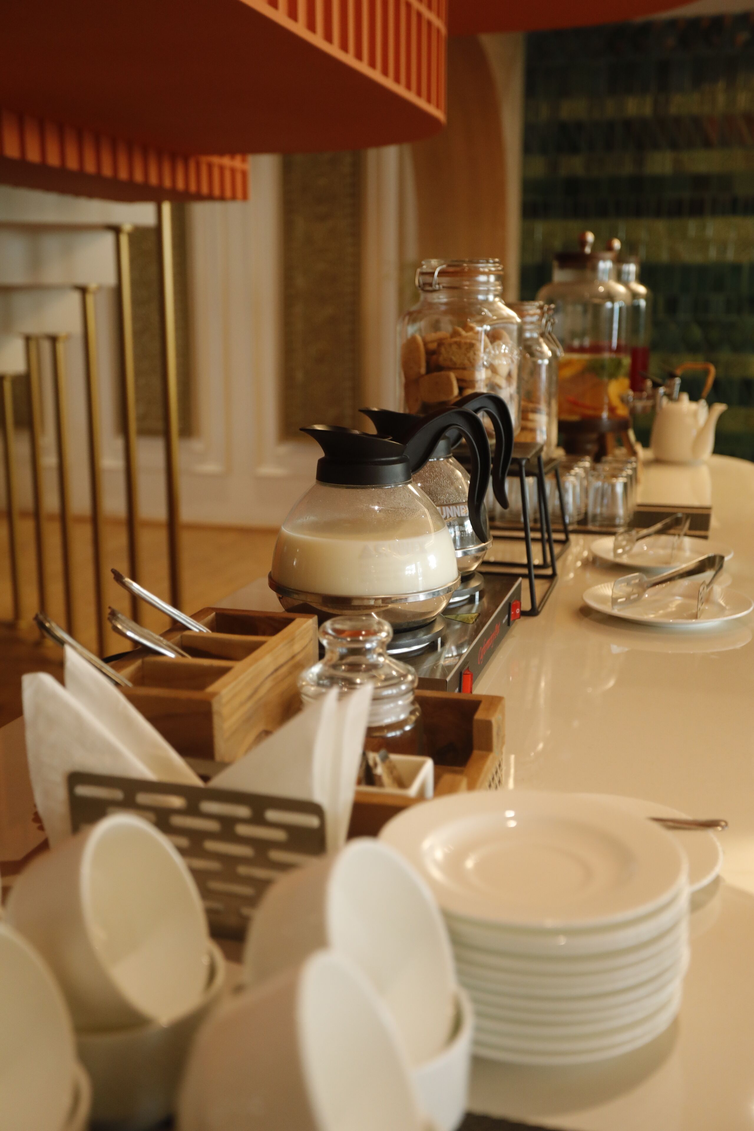 A breakfast buffet setup with various dishes, utensils, and condiments.