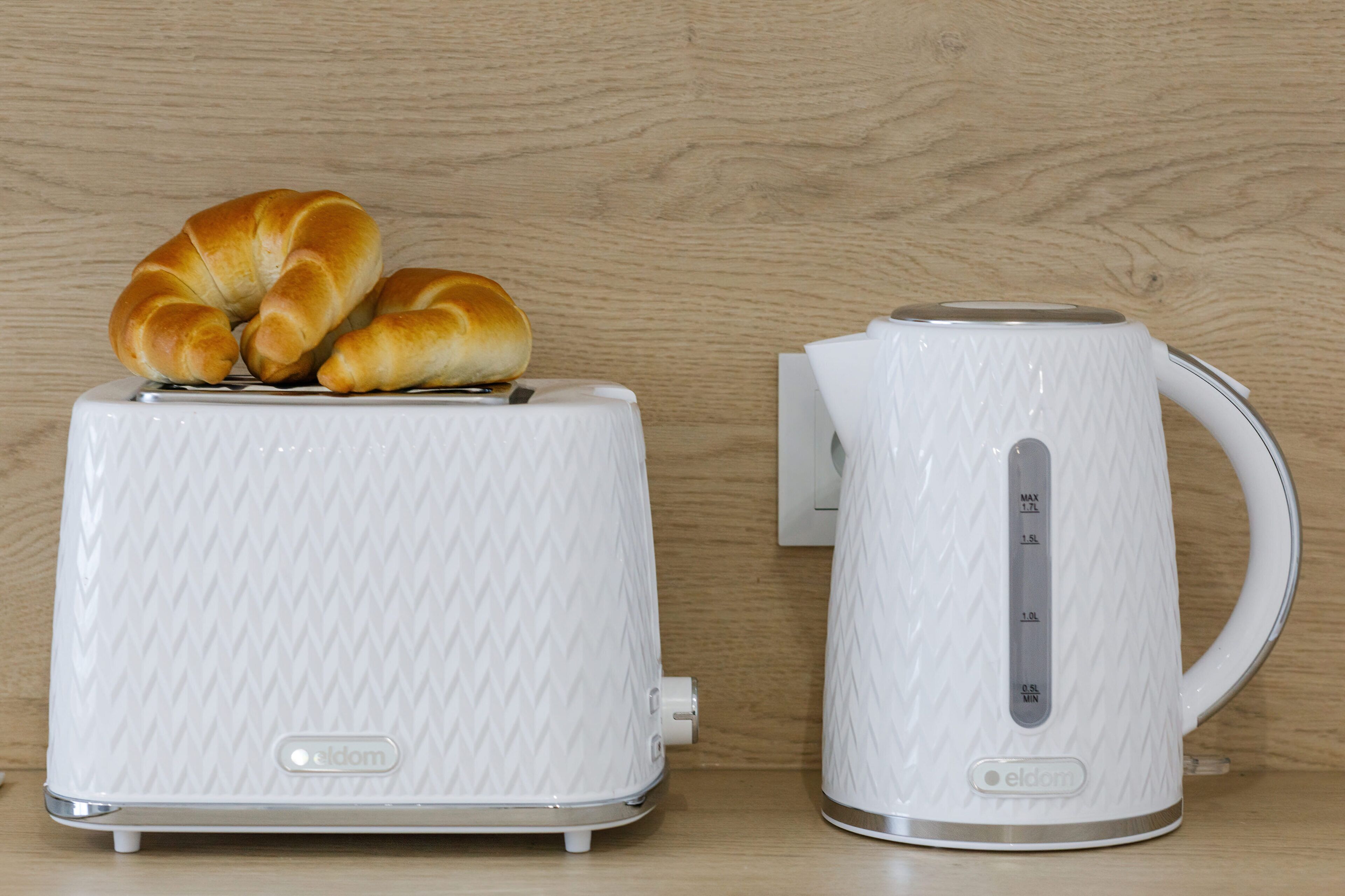 A white toaster and kettle with a wooden background.