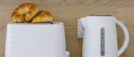 A white toaster and kettle with a wooden background.