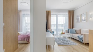 Een moderne woonkamer met een bank, een salontafel en een bed met een roze deken.