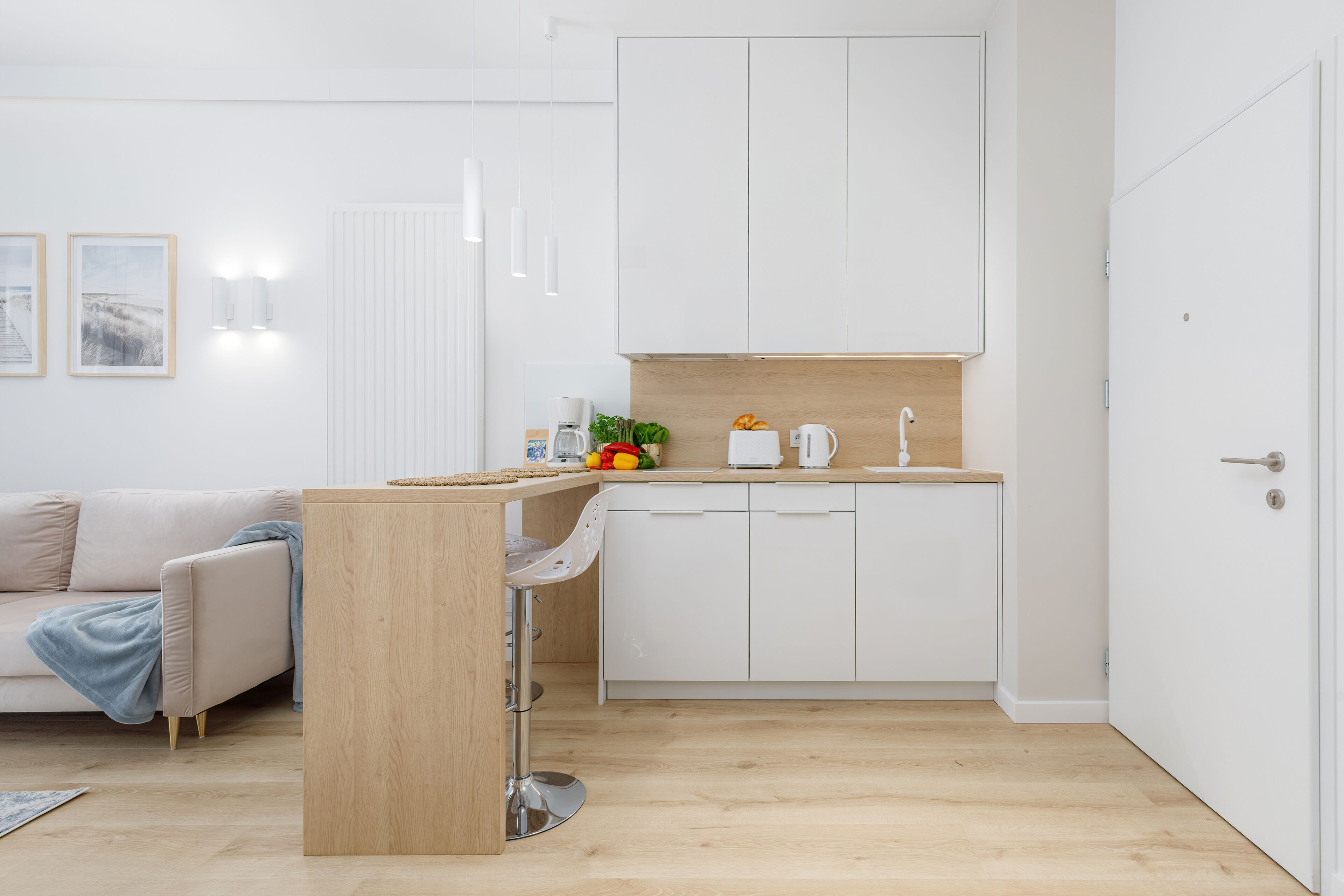 Una cocina compacta con armarios blancos, encimera de madera y un lavamanos.