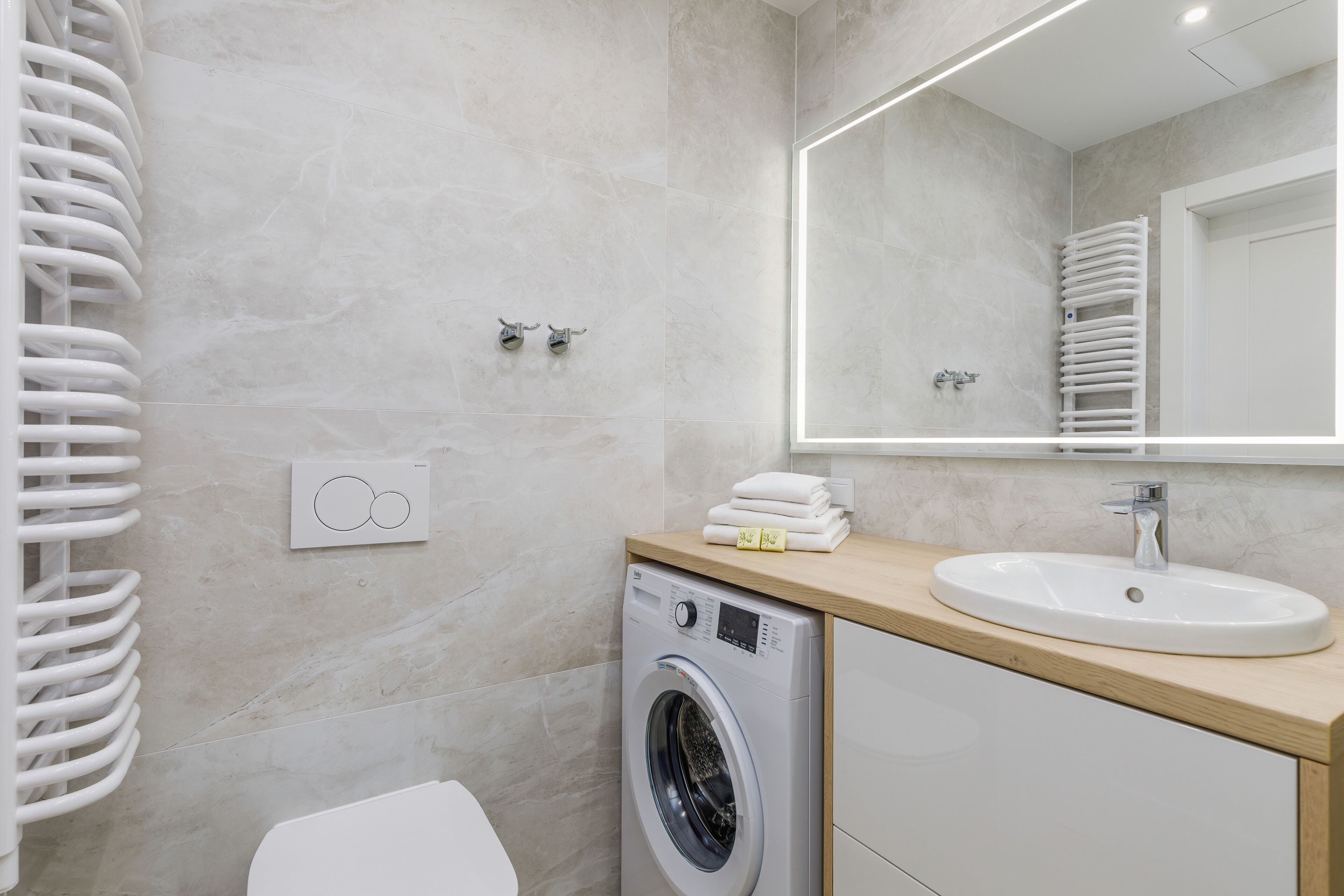 A modern bathroom with a built-in washing machine, a sink, and a large mirror.