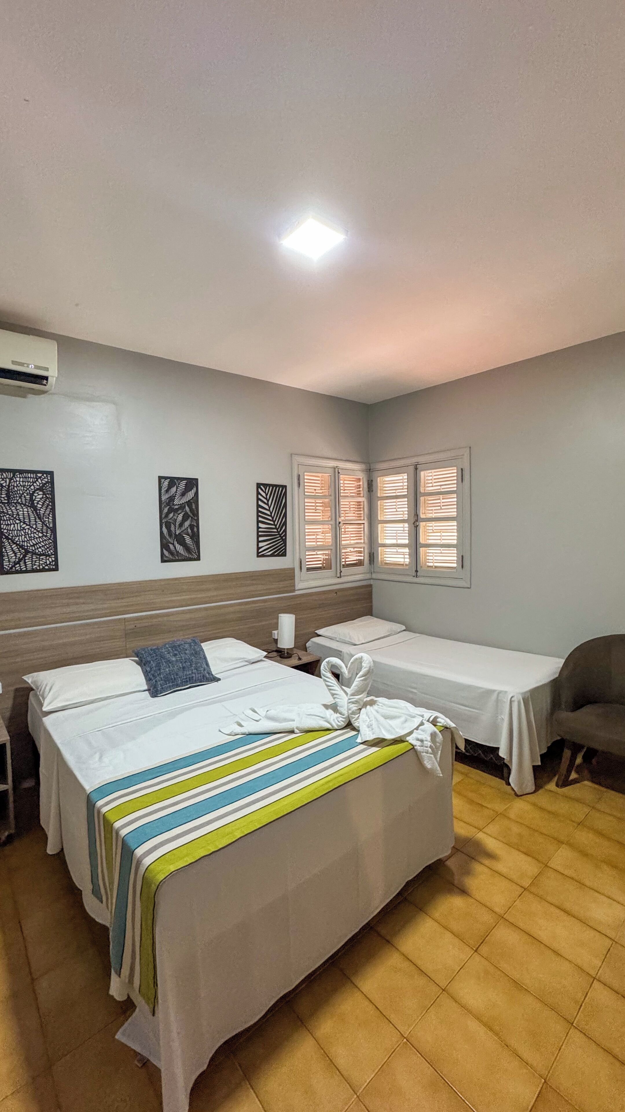 Habitación de hotel con cama, una silla, escritorio y ventana con persianas.