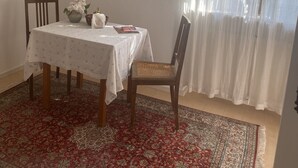 A dining area with a table set for two, a chair, a vase with flowers, and a book. - Ferienwohnung auf dem Bauernhof, Idyllisch am Stadtrand von Kaufbeuren (Kaufbeuren)