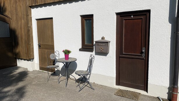 A building with a white exterior, two wooden doors, a small window, and a mailbox. - Ferienwohnung auf dem Bauernhof, Idyllisch am Stadtrand von Kaufbeuren (Kaufbeuren)