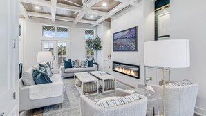 Una sala de estar amplia con chimenea, muebles modernos y un ventilador de techo.