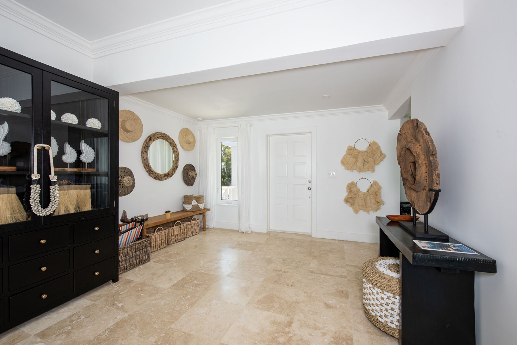 A spacious hallway with a black cabinet, a bench, and decorative items on the walls.