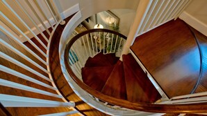 A spiral staircase with wooden steps and white railings. - Beachfront Bliss with Gulf Views & Heated Pool (Holmes Beach)