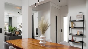 A modern dining area with a wooden table, grey chairs, and a white vase with pampas grass.