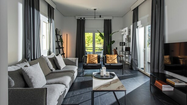 A modern living room with a sofa, chairs, a coffee table, and a TV.