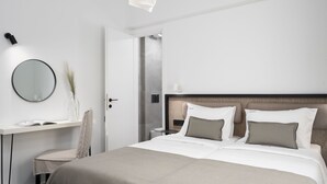 A modern hotel room with a bed, bedside table, and a mirror.