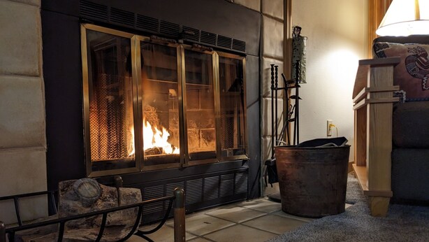 A fireplace with a glass door, a wooden bench, and a large metal pot. - Incredible MTN Views | In-Town | Pool | Hot Tub (Durango)