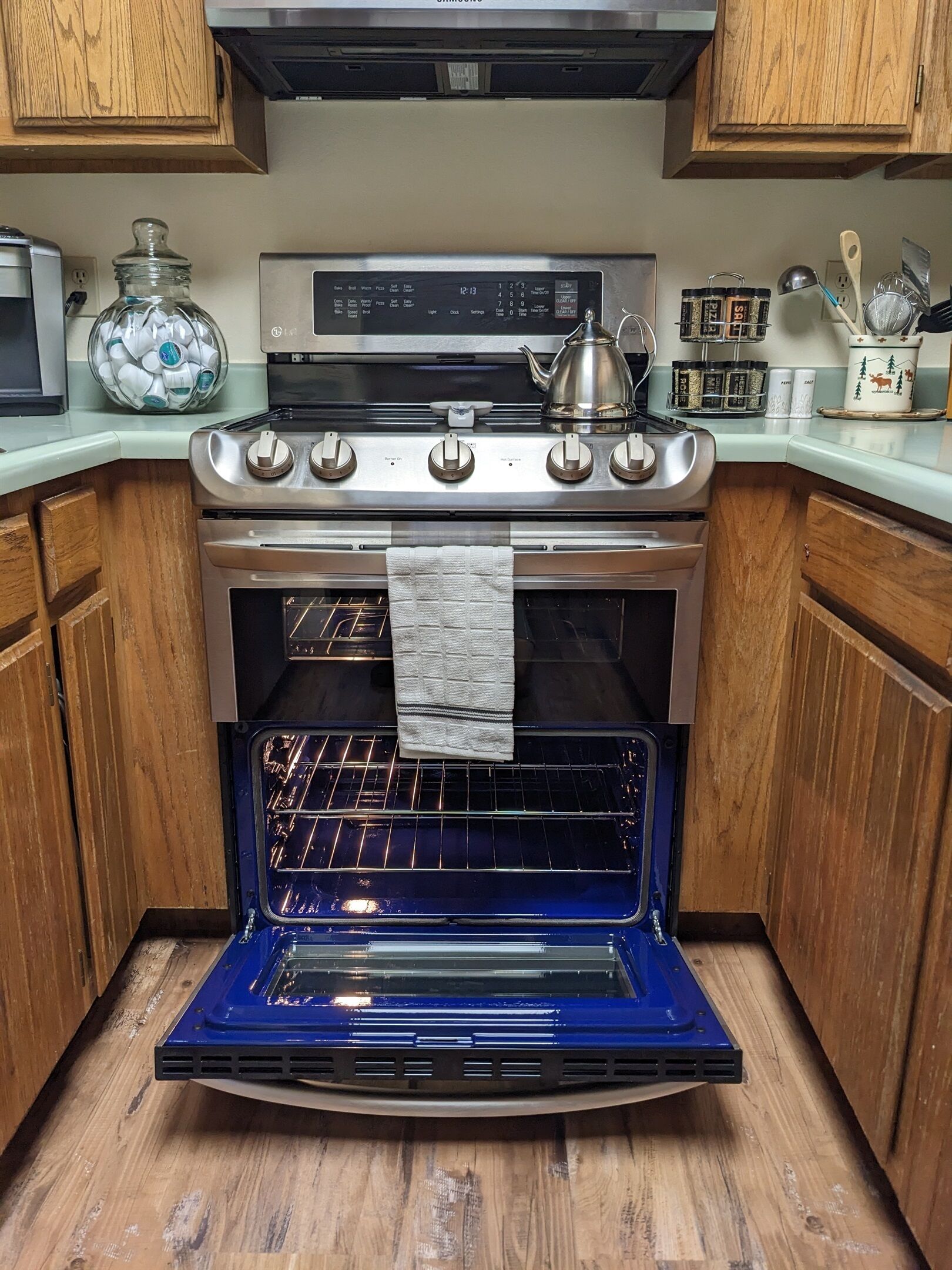 Una cucina con forno in acciaio inossidabile, mobili in legno e sportello del forno blu.