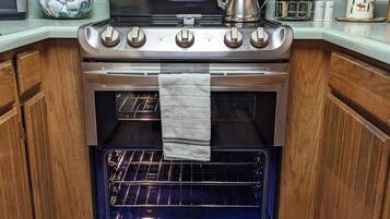 Una cucina con forno in acciaio inossidabile, mobili in legno e sportello del forno blu.
