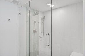 Een glazen douchecabine met een handdouche en een wandmengkraan.