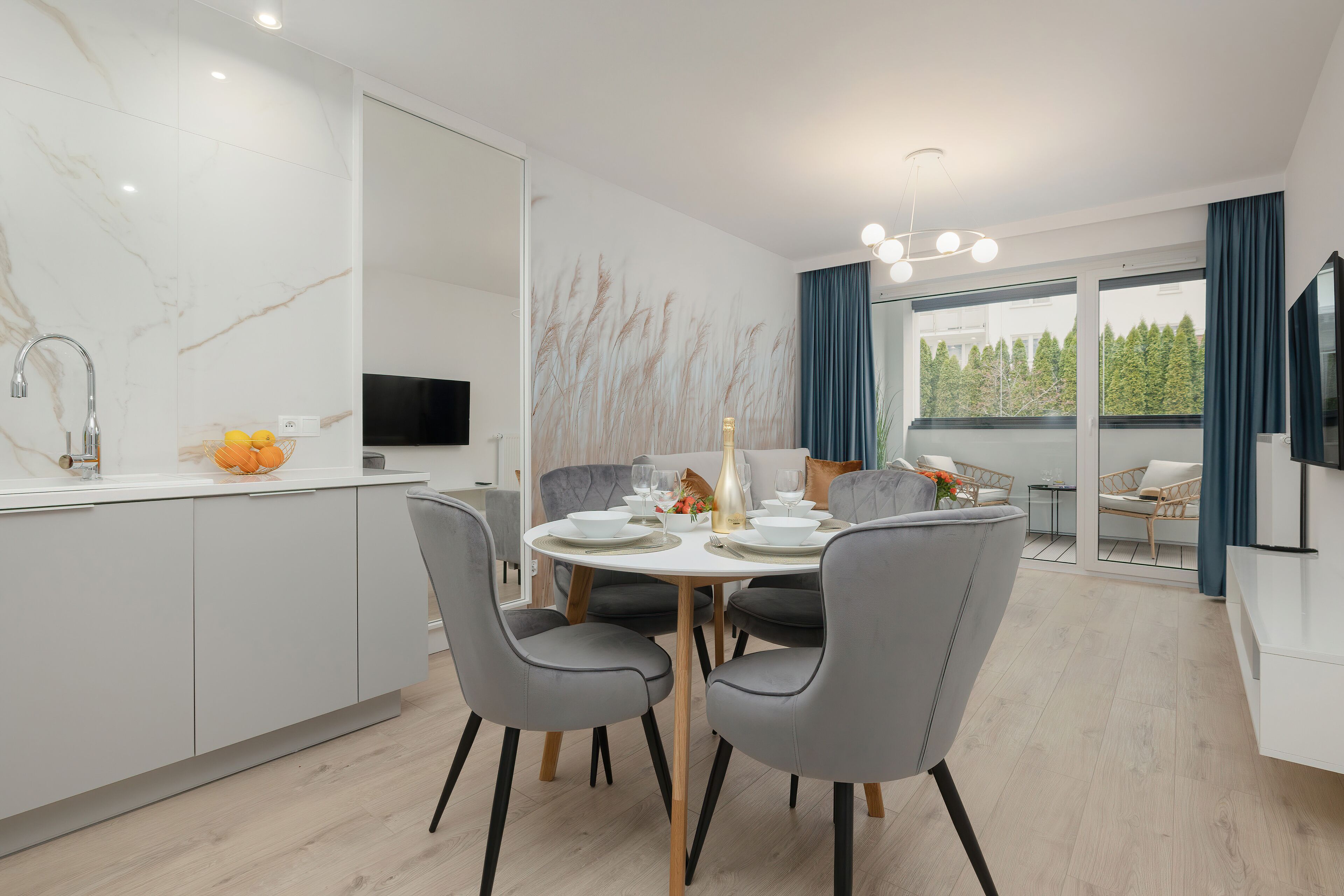 Una cocina moderna con comedor, televisor integrado y un amplio ventanal con cortinas.