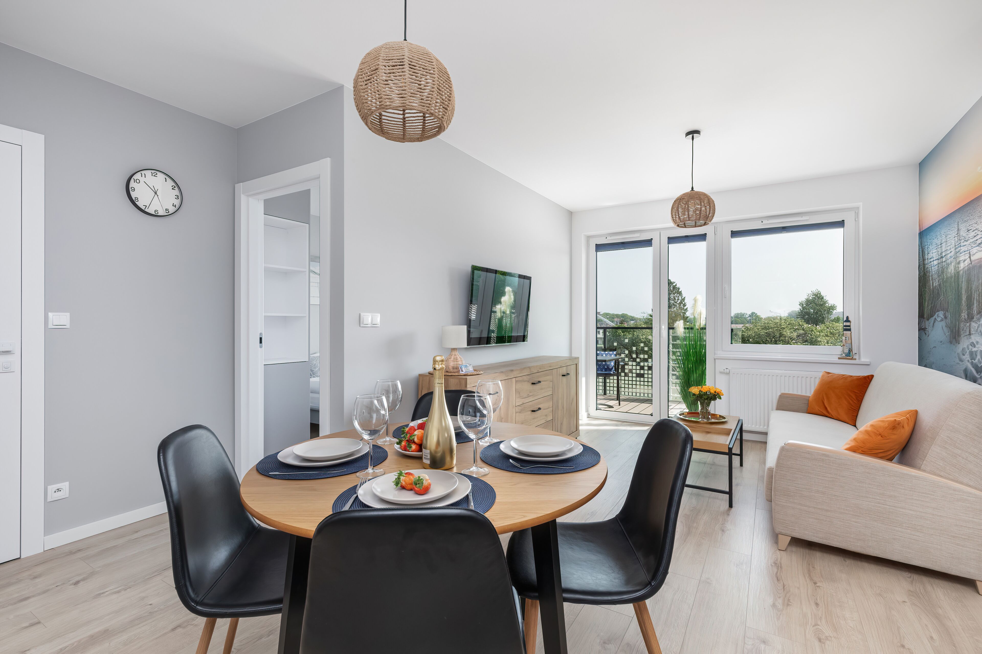 A modern dining area with a round table, black chairs, and a white sofa in the background.