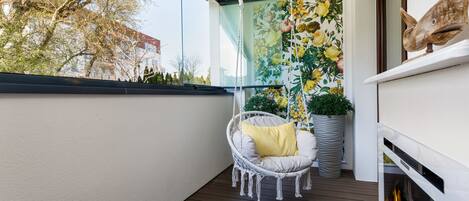 A balcony with a hanging chair, a potted plant, and a fireplace.