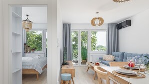 Un espacio habitable y comedor moderno y abierto, con una cama, una mesa de comedor preparada para dos personas y un sofá.