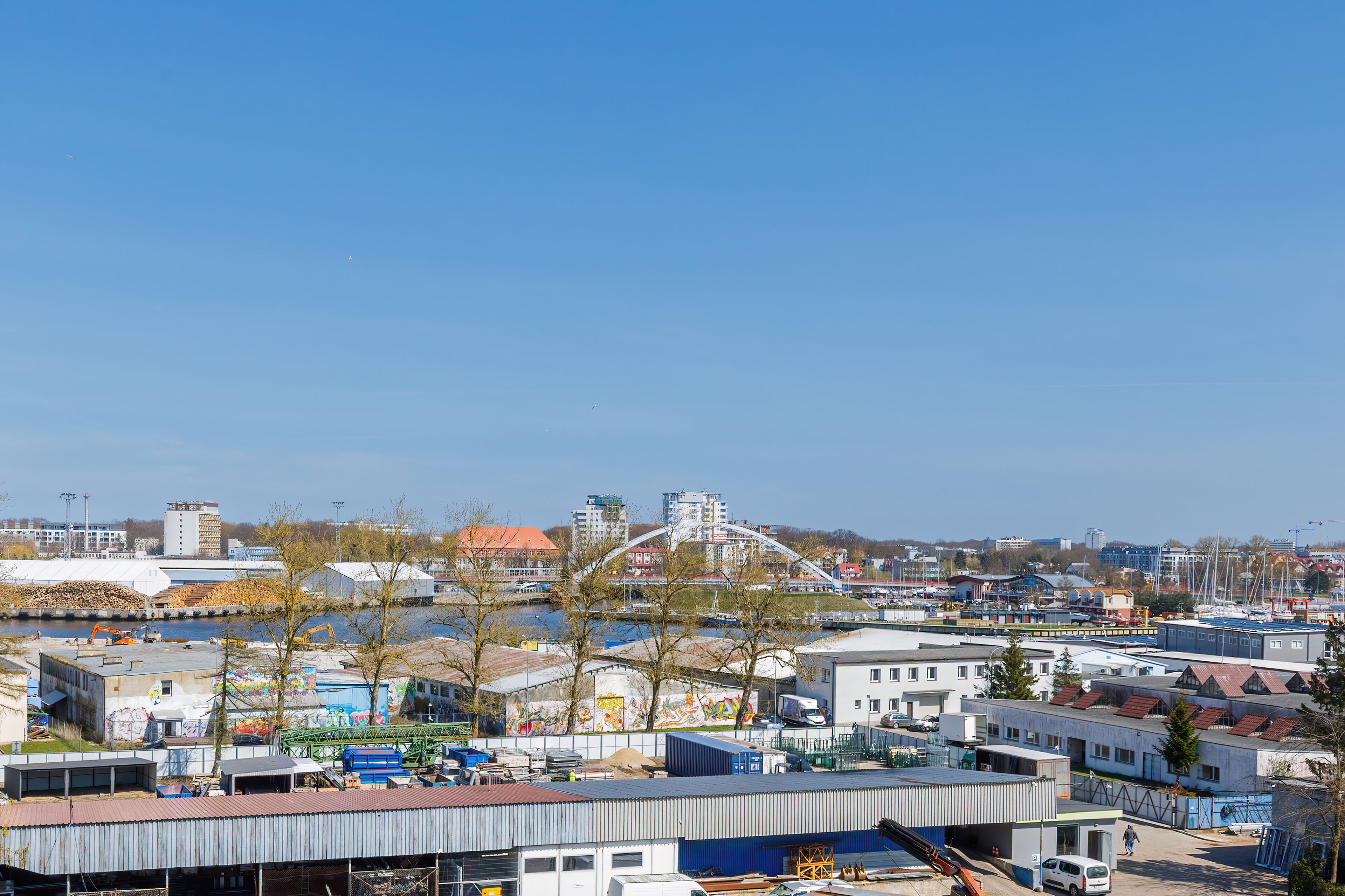 En vy över ett industriområde vid en flod, med lagerbyggnader, en bro och själva floden.