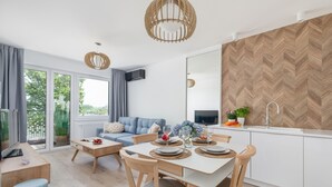 Una sala moderna con sofá, mesa de centro y mesa de comedor con sillas. Cuenta con una zona de cocina con pileta y salpicadero con diseño tipo espiga.