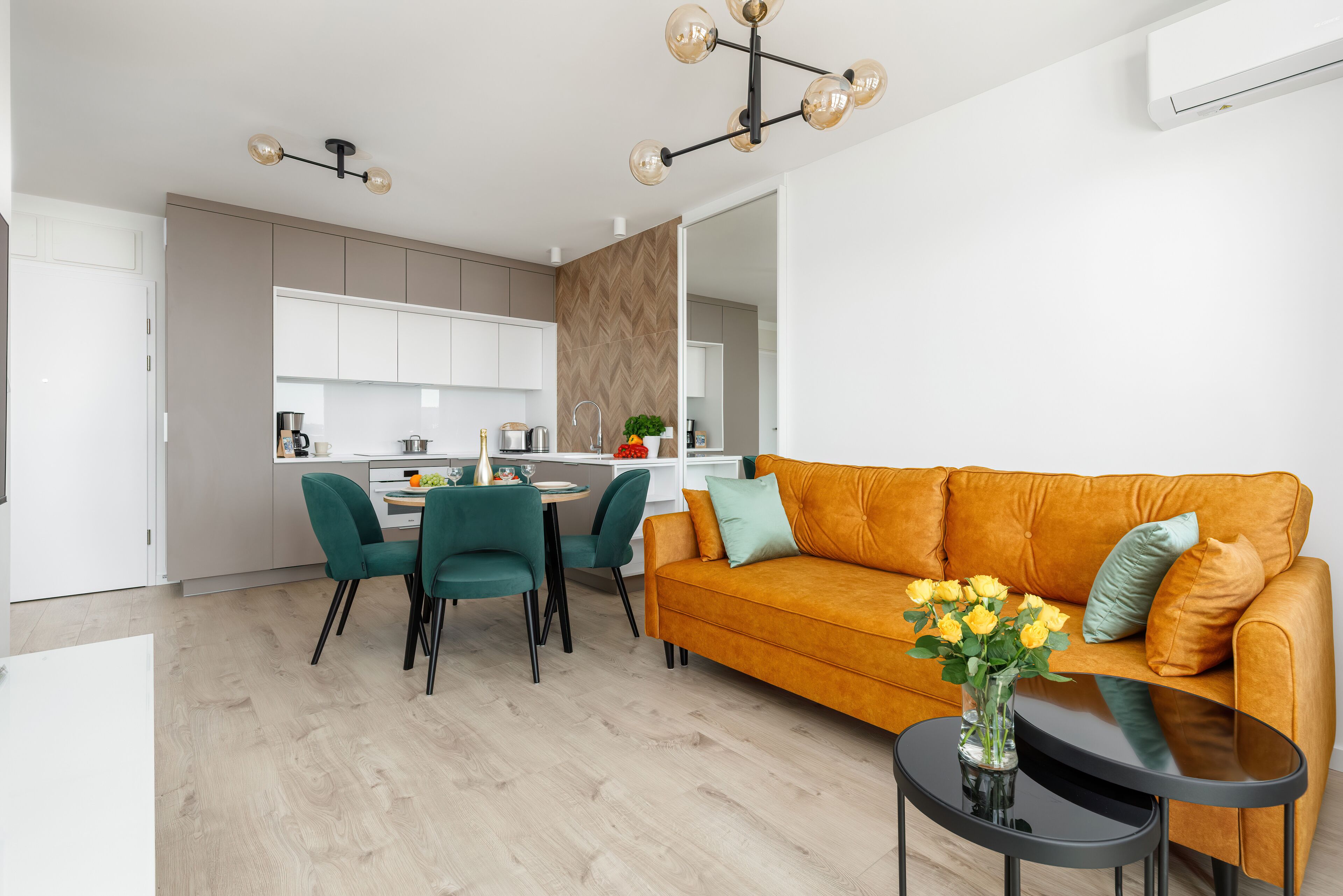 A modern living room with a sofa, a coffee table, and a dining area with chairs and a table.