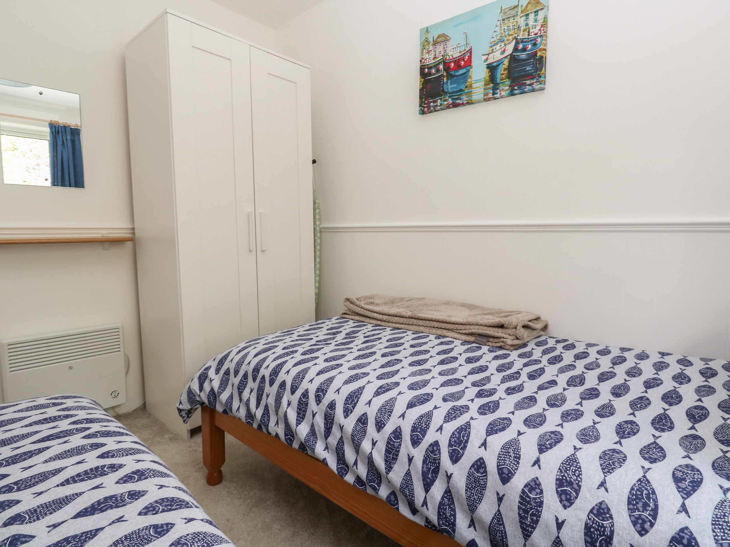 Una camera da letto con due letti singoli, un armadio, un termosifone e un quadro appeso al muro.